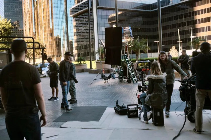 Film crew working on a Los Angeles street with production trucks in the background
