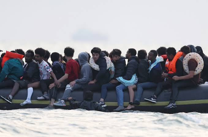 Migrants on a beach in northern France with authorities in the background