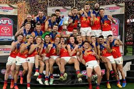 Brisbane Lions players celebrating with the premiership cup on the MCG turf