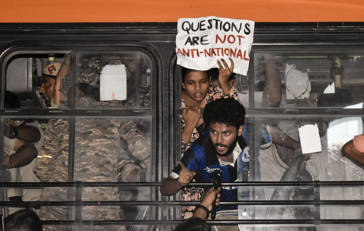 Crowd of protesters in New Delhi with police barricades in the background
