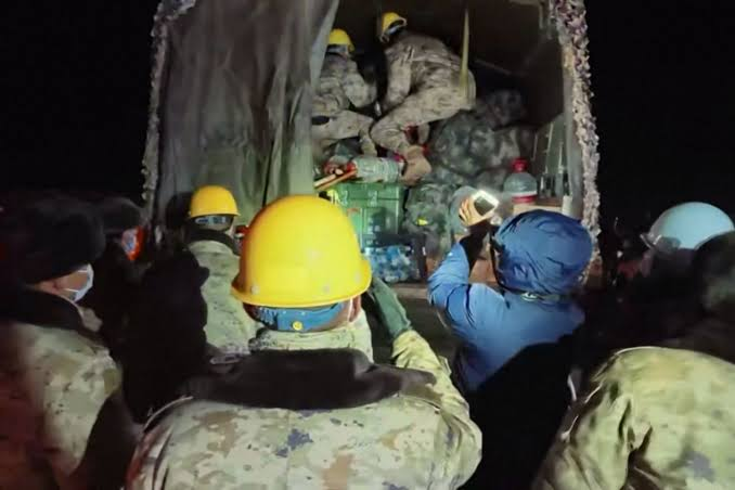 Rescue workers and damaged buildings in a mountainous area after an earthquake