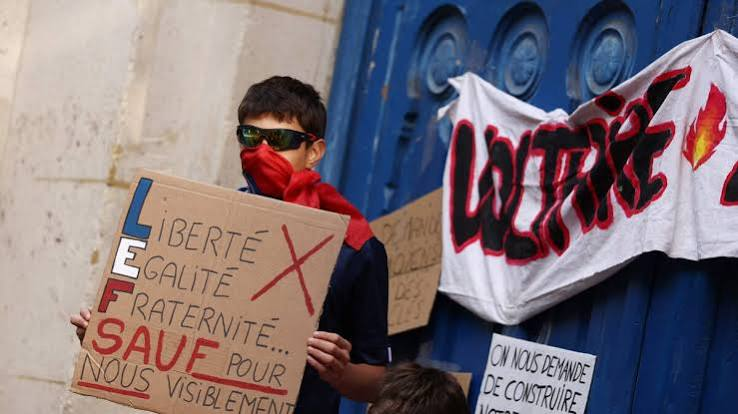 High school students marching and holding banners during a protest in a French city