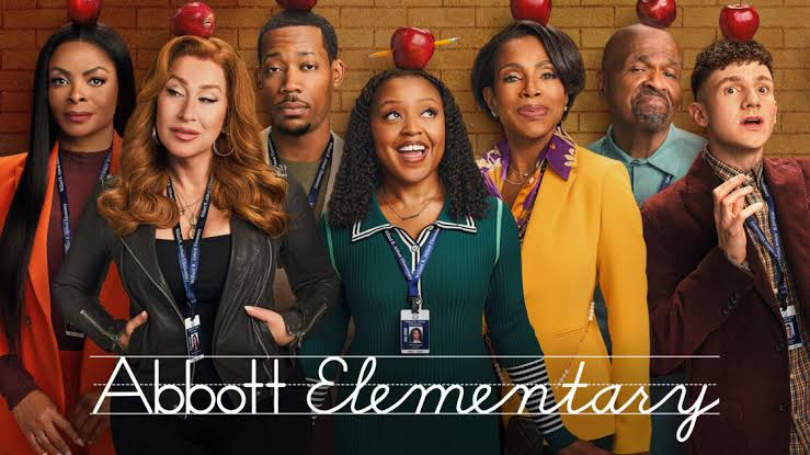 Abbott Elementary cast standing in a classroom smiling