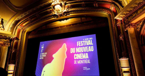 Crowd outside a Montreal cinema at night with FNC banners
