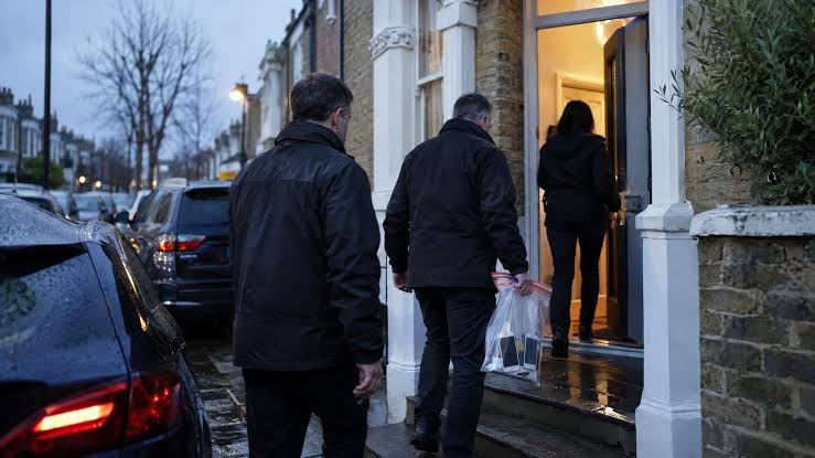 Police officers outside residential premises during early morning enforcement raids