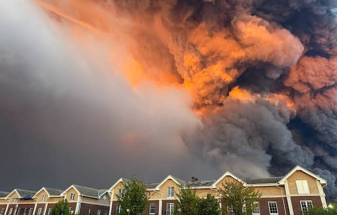 Industrial complex with smoke and emergency response vehicles (stock image)