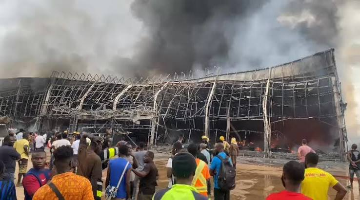 Smoke rising behind a retail complex as fire crews work