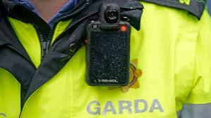 A smartphone showing a social media feed with an alert overlaid, beside an An Garda Siochana badge.