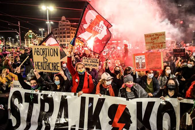 Protesters hold banners and red placards during an abortion rights demonstration in Warsaw