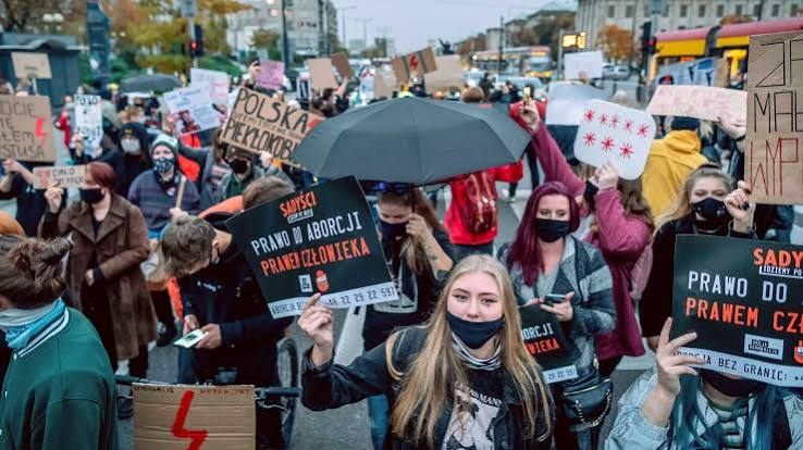 Protesters hold banners and red placards during an abortion rights demonstration in Warsaw